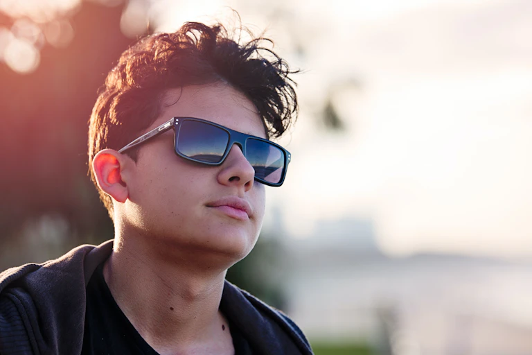 Portrait of teenager wearing sunnies, with neutral expression.