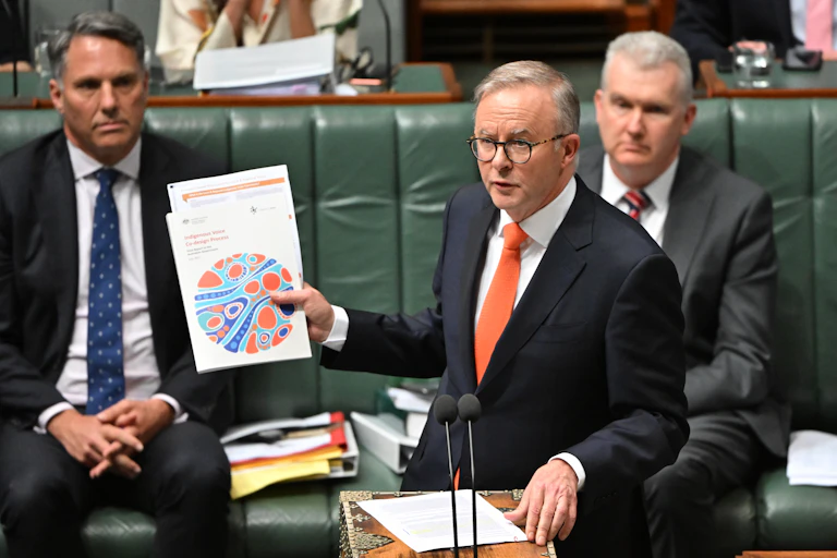 Anthony Albanese holding up Voice documents