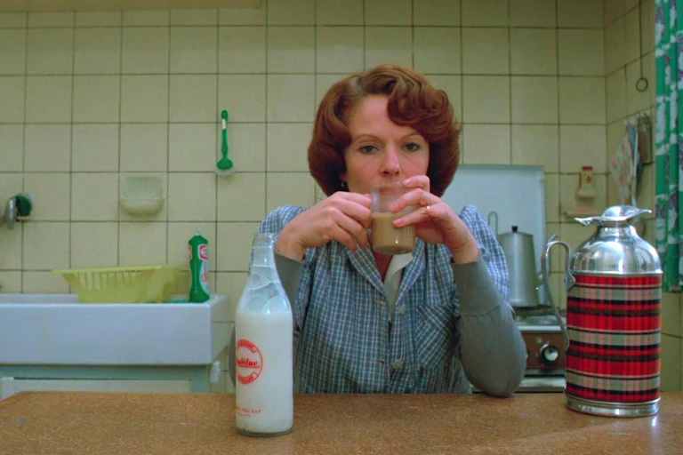 A woman sits drinking tea in her kitchen.