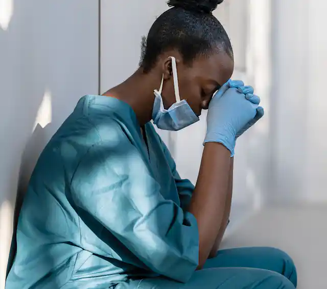 Photo of stressed nurse with head in her hands.