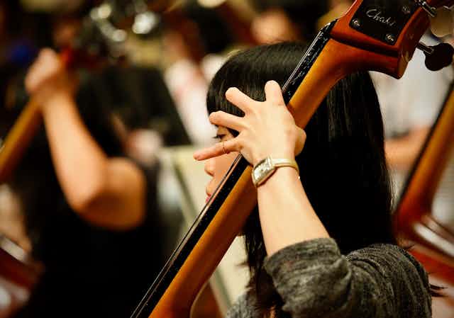An Asian woman plays a cello