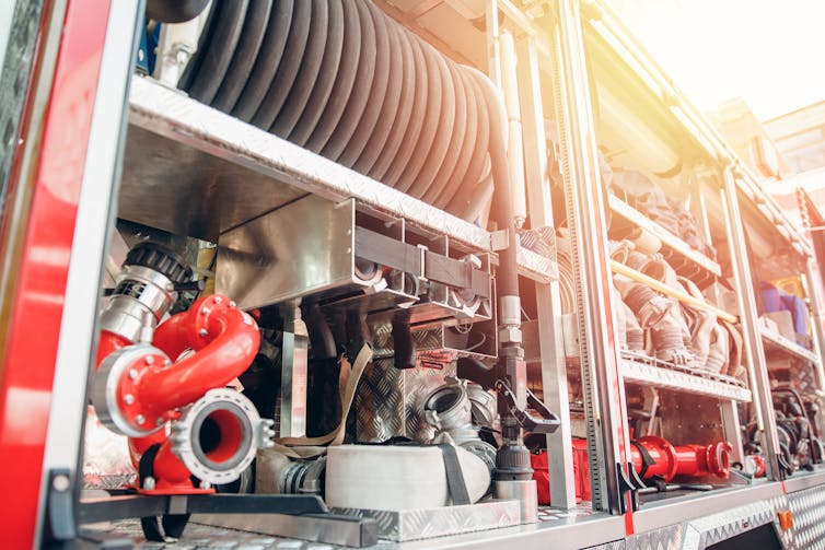 Pipes and bits of equipment in racks at the back of a fire truck.