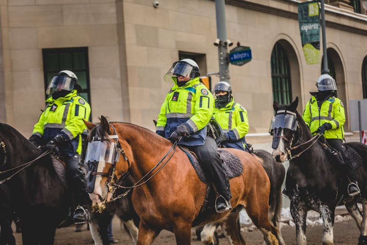 Police wearing high visibility jackets on horseback.