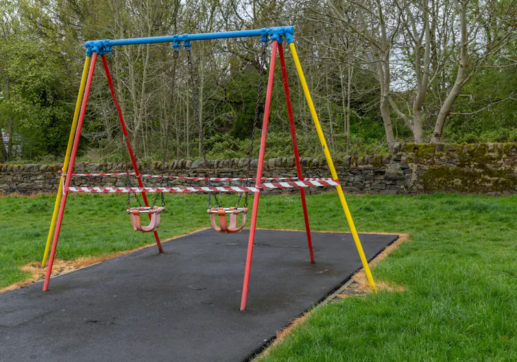 A swing set with warning tape around it.