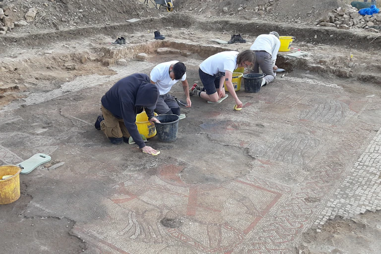 Archaeology students and ULAS staff from University of Leicester carefully clean the fully exposed Trojan War mosaic.