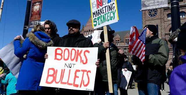 A protest with a man holding a sign that reads: books not bullets.