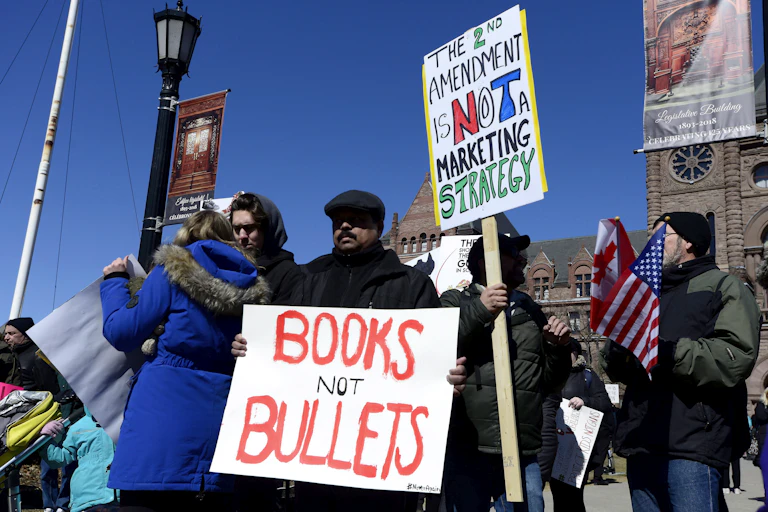 A protest with a man holding a sign that reads: books not bullets.