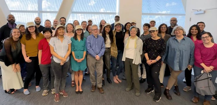 A diverse group of over 30 people standing together and smiling at the camera