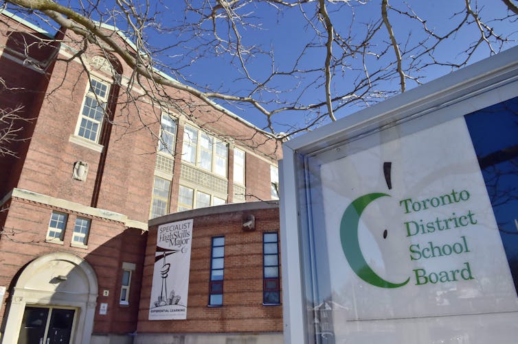 A sign that reads: Toronto District school board in front of a brown building.