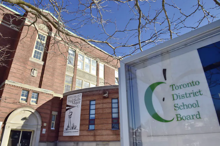 A sign that reads: Toronto District school board in front of a brown building.
