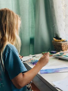 A young girl paints with watercolours.