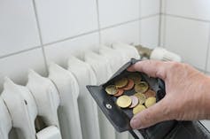 Hand opening a wallet and revealing change in front of a white radiator.