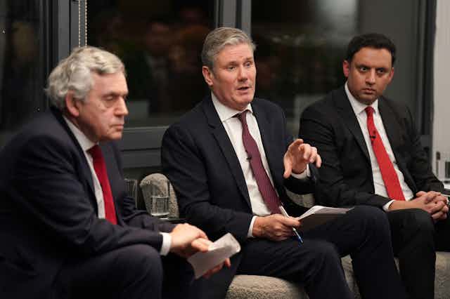 Gordon Brown Keir Starmer and Anas Sarwar sitting in a row, talking to an audience. 