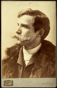 Sepia portrait shows Henry Wellcome with short hair and a huge handlebar moustache.