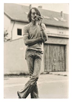Vintage photo from young fashion smoking man wearing typical 1970s clothing. Retro picture with original film grain and scratches.