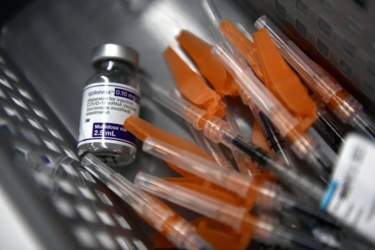 A vial of vaccine and a pile of syringes