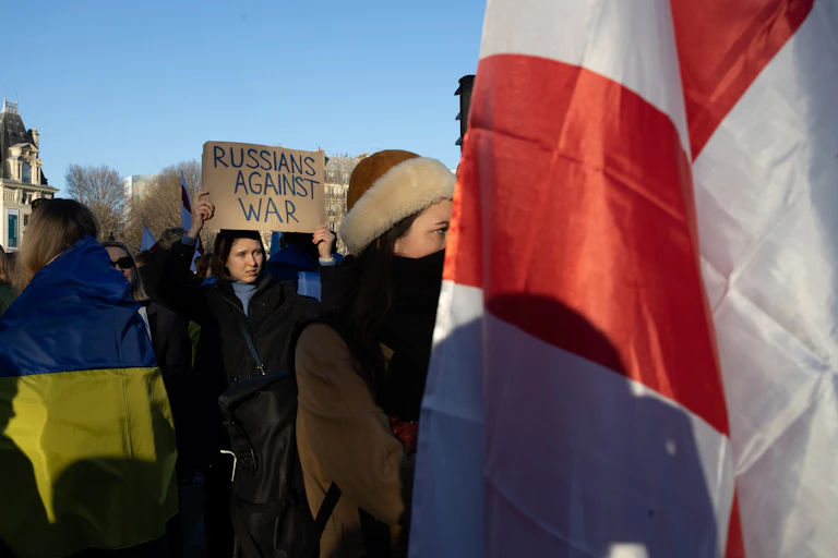 Femme brandissant une pancarte « Russians Against War » pendant une manifestation