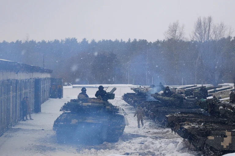 Tanks lined up opposite a tank with two soldiers in it.