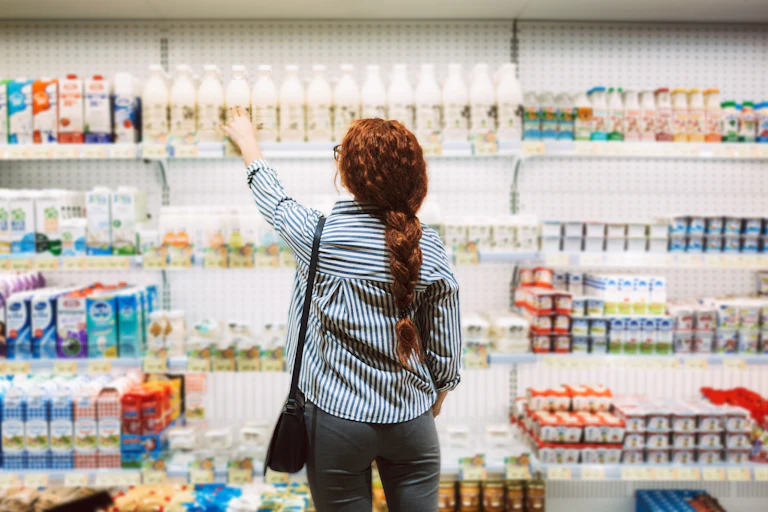 Person reaching for a bottle on a grocery store shelf