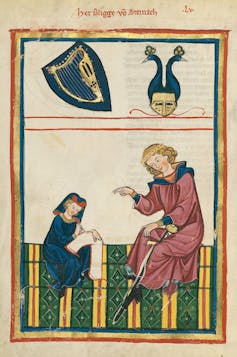 An old manuscript page shows a large figure in a pink robe dictating to a small scribe wearing a blue one.