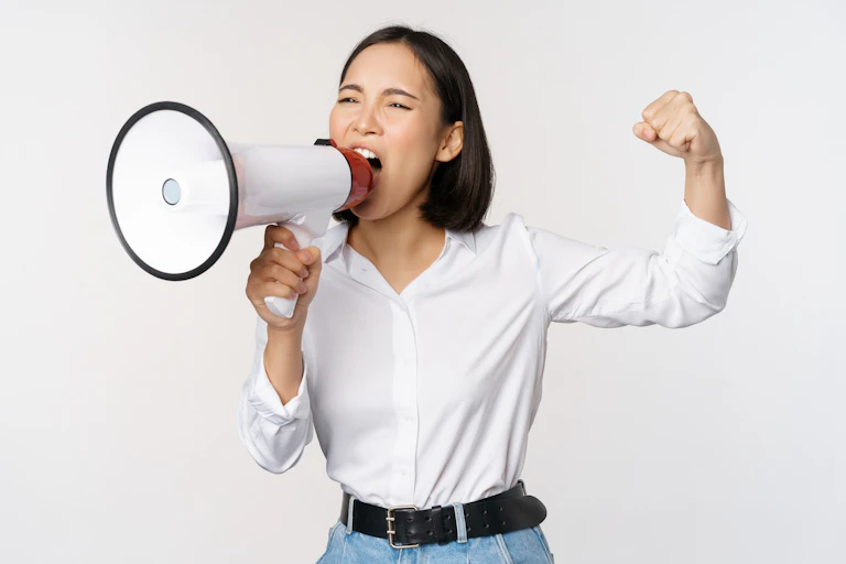 Woman shouting into a megaphone, one hand raised in a fist.