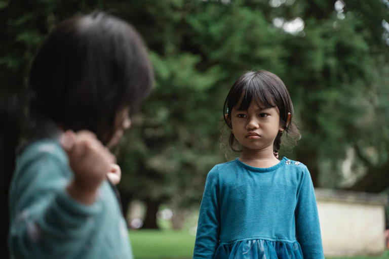 Two young girls squabble over an object in a park.