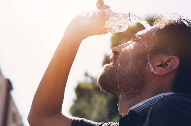 Man pours water over his face on a hot day