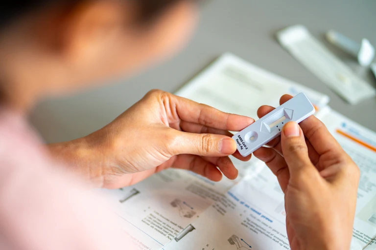 Woman holding and looking at rapid antigen test cartridge