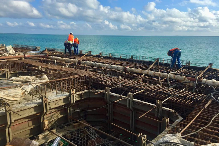 Three men working on a construction site by the sea