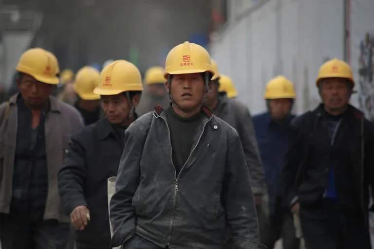A group of men wearing yellow hard hats walking.