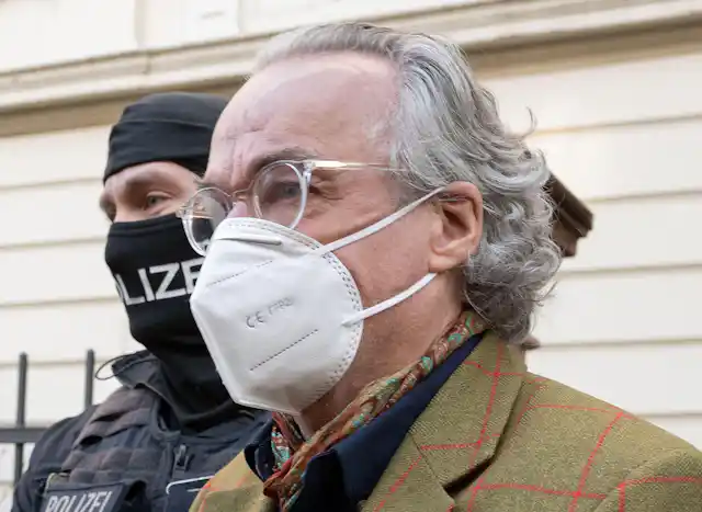 Heinrich XIII Prince Reuss wearing a face mask with a masked police officer behind him.