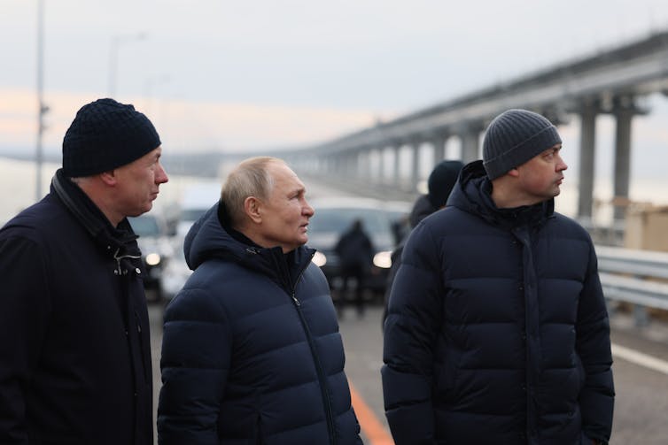 Vladimir Putin and aides inspect repair work at a bridge.