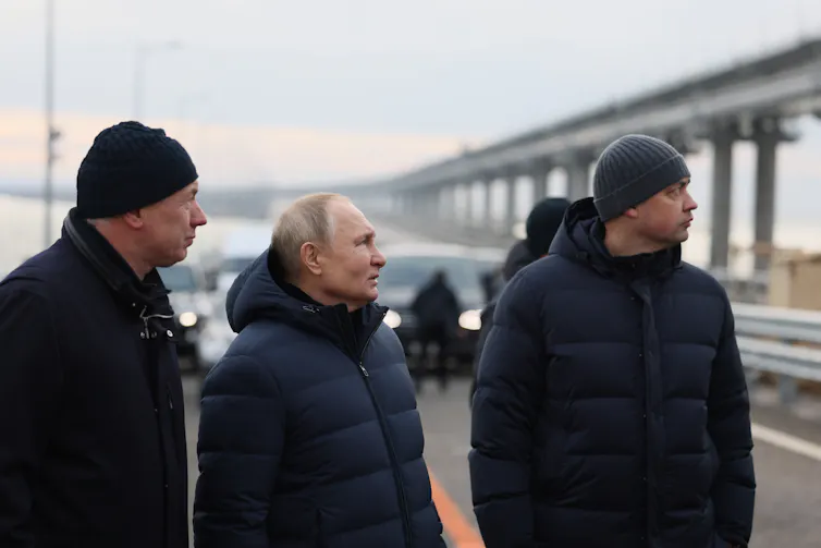 Vladimir Putin and aides inspect repair work at a bridge.