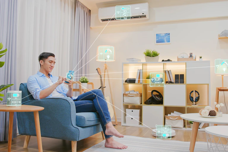 Un homme assis dans son fauteuil contrôle des objets connectés avec son téléphone.
