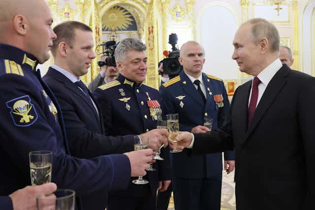 Russian president Vladimir Putin drinks champagne with military officers at a function in Moscow.