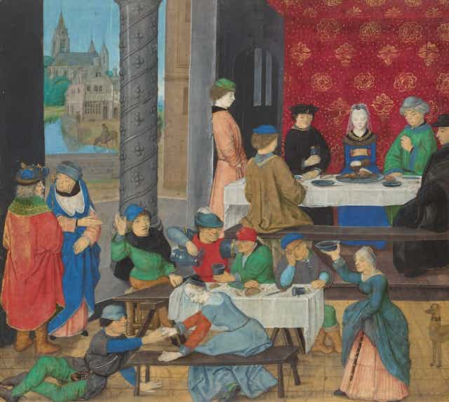 People gathered both standing and sitting in a medieval building.