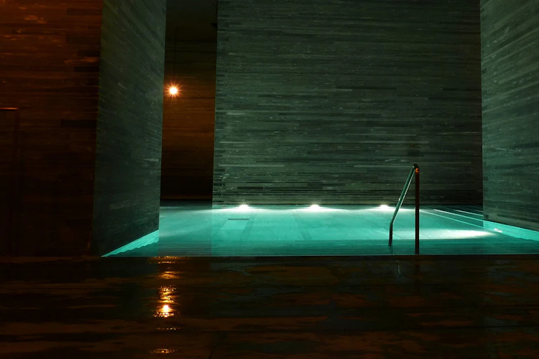 A railing seen beside a spa bath lit with low lights.