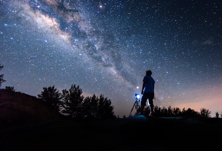 Silhouette of a person looking at the night sky in front of the camera.