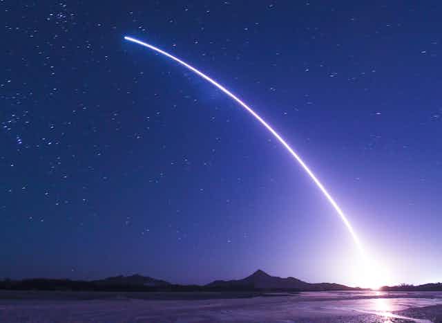 A rocket launch streaking across a starry sky.