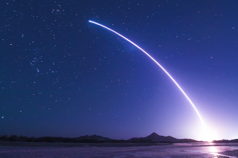 A rocket launch streaking across a starry sky.