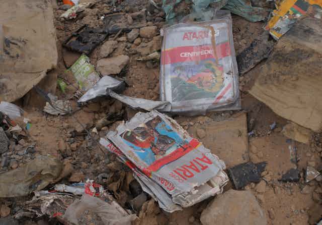 Crushed, dusty Atari games in the dirt from a landfill.