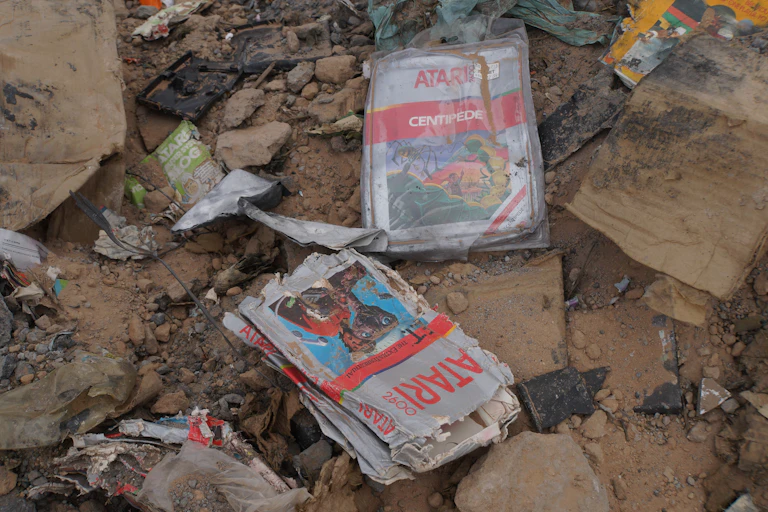 Crushed, dusty Atari games in the dirt from a landfill.