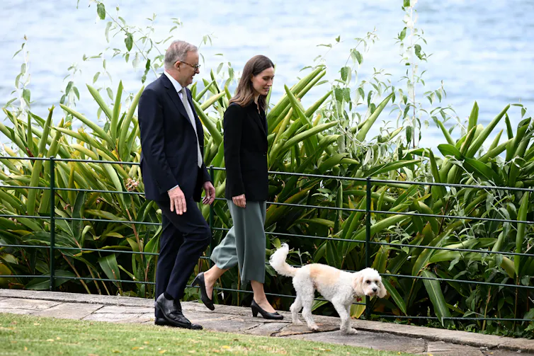 man and woman walk dog