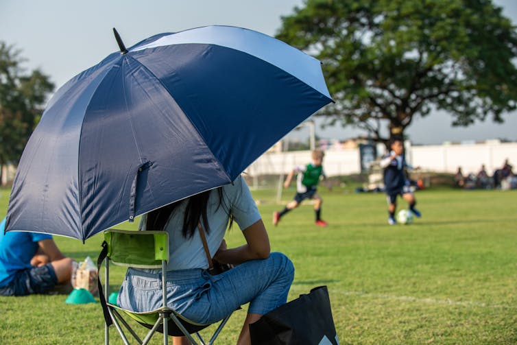 A woman watches children play sport.