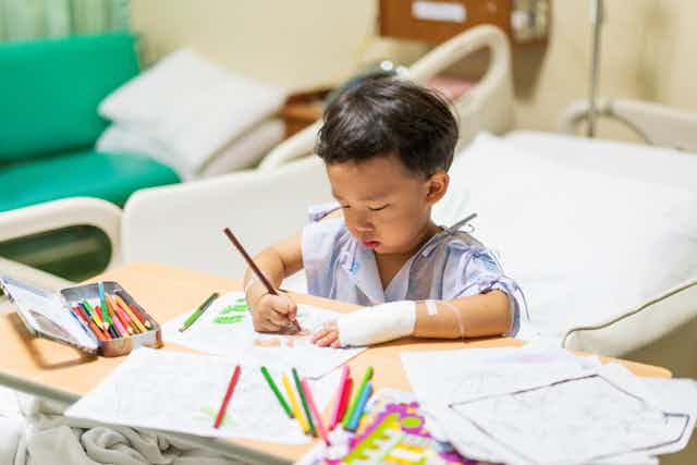 Young boy drawing in a hospital bed