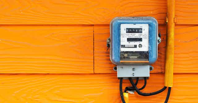 Electricity meter mounted on orange wall