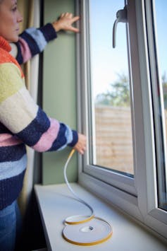 Woman stands by window with tape