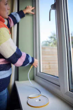 Woman stands by window with tape
