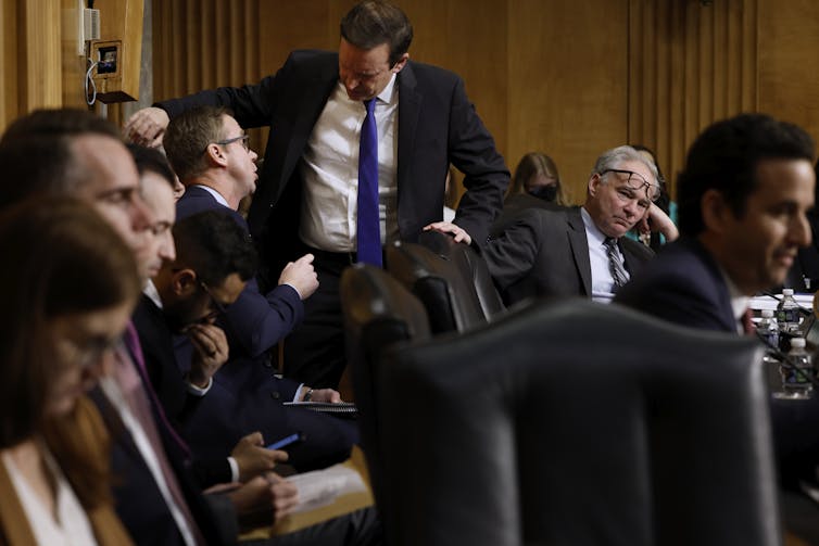 A bunch of tired-looking men in suits at a meeting.