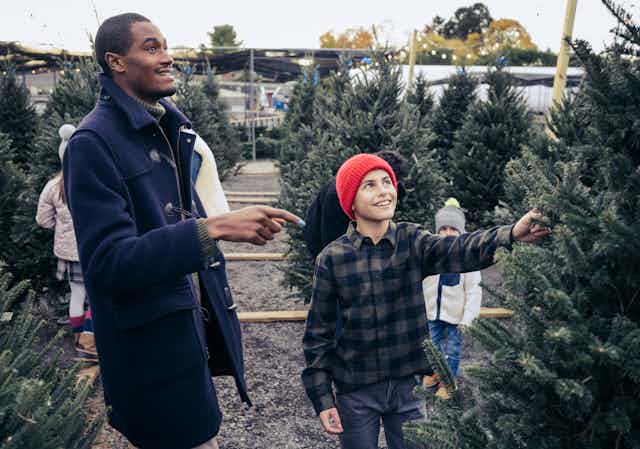 man and boy pointing to a pine tree on a retail lot